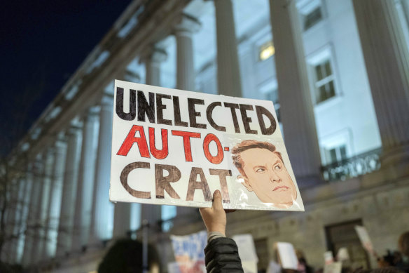 People protest during a rally against Elon Musk outside the Treasury Department in Washington.