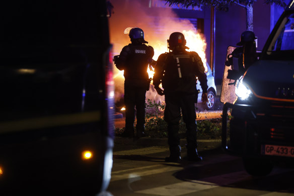 Riot police stand near a burning car in the La Meinau neighbourhood of Strasbourg.
