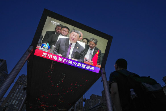 A man watches a large screen showing CCTV broadcasting news of Chinese President Xi Jinping delivering his speech at the BRICS Summit held in South Africa, at an outdoor shopping mall in Beijing.