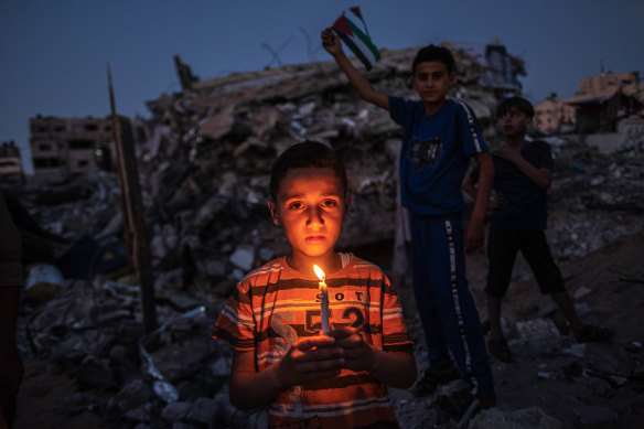 Palestinian children hold a candle and the Palestinian flag amid the ruins in Beit Lahiya in the Gaza Strip.  