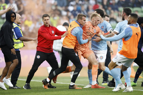 A bleeding Tom Glover of Melbourne City is escorted from the pitch by teammates.