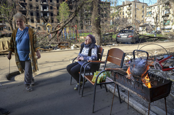 Women cooking in the entrance of a damaged apartment in Mariupol, which has been without heating or power since the first week of the war. 