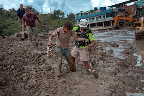 A rescuer assists a resident through heavy mud following the floods in Trishuli, Nepal.