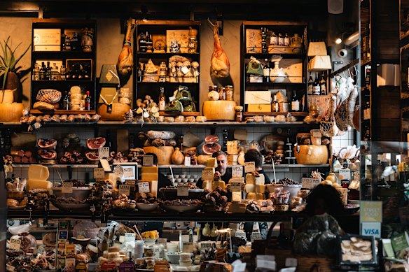 A shopkeeper hidden behind the counter of a traditional Italian delicatessen. 