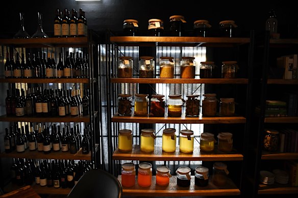 Spotlit shelves are filled with jars of ferments.  
