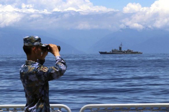A People’s Liberation Army member watches military exercises, with Taiwan’s frigate Lan Yang in the background.
