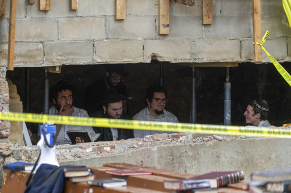 Hasidic Jewish students sit behind a breach in the wall of a synagogue that led to a tunnel.