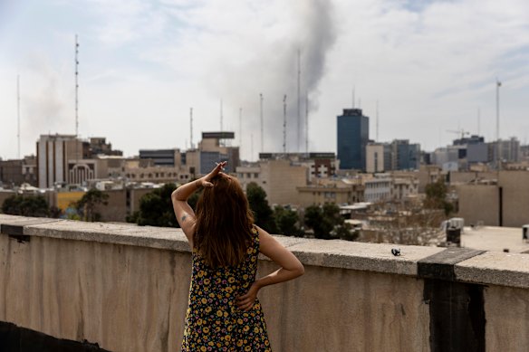 Seorang wanita melihat asap yang mengepul dari serangan udara baru-baru ini di Tehran pada 7 Maret.