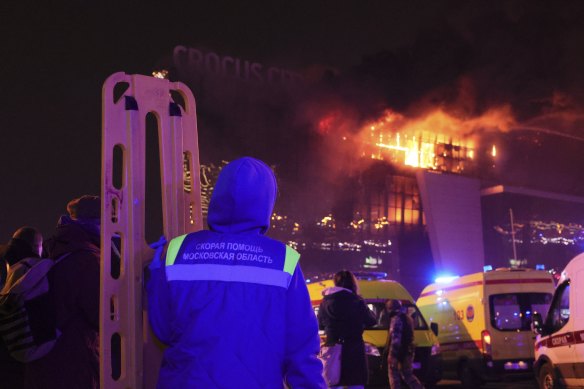 A medic stands near ambulances parked outside the burning building of the Crocus City Hall on the western edge of Moscow, Russia.