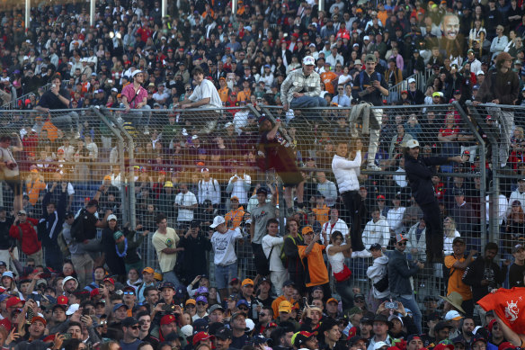 Fans scale the fence and enter the track at Albert Park.