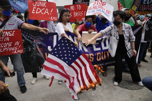 Demonstrators burn a mock U.S. flag as they protest against the visit of US Defence Secretary Lloyd Austin.