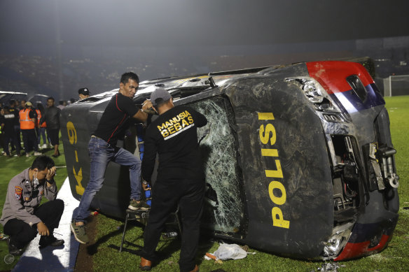 Officers examine a damaged police vehicle following a clash between supporters of two Indonesian soccer teams at Kanjuruhan Stadium in Malang, East Java, Indonesia.