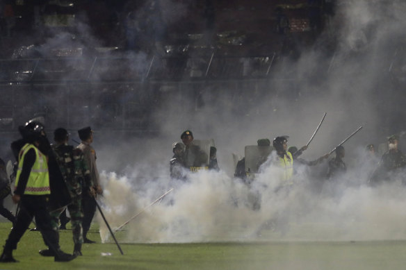 Polis memurları ve askerler Cumartesi günü Kanjuruhan Stadyumu'nda göz yaşartıcı gaz dumanı arasında duruyorlar.