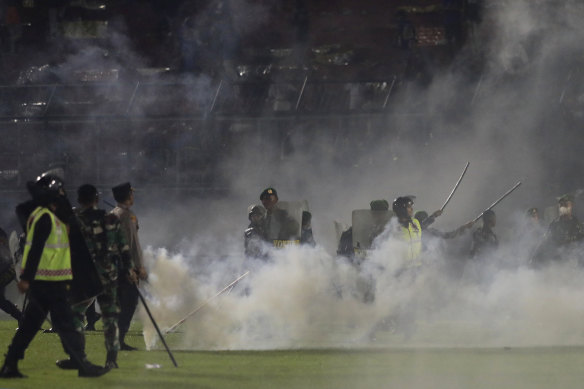 Police officers and soldiers stand amid tear gas smoke at Kanjuruhan Stadium on Saturday.