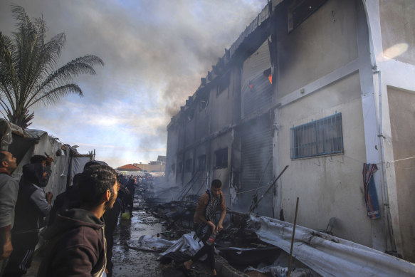 Palestinians try to extinguish a fire at a building of an UNRWA vocational training centre which displaced people use as a shelter, after being targeted by Israeli tank shill in Khan Younis.
