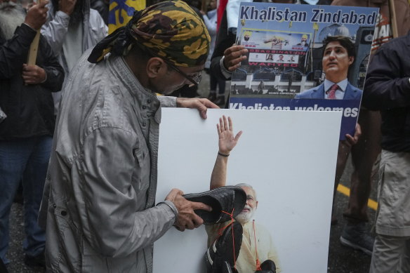 A protester hits a photograph of Indian Prime Minister Narendra Modi with a sandal during a protest outside the Indian consulate in Vancouver.