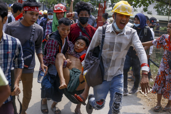 Anti-coup protesters carry an injured man following clashes with government forces in Yangon, Myanmar in March, 2021. 