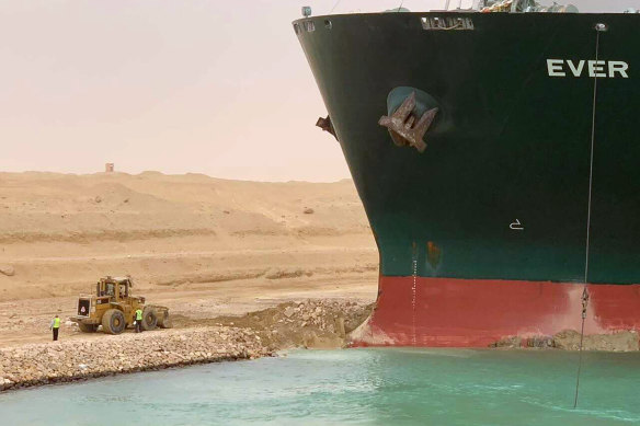 The Ever Given sits with its bow stuck into the wall of the Suez Canal.