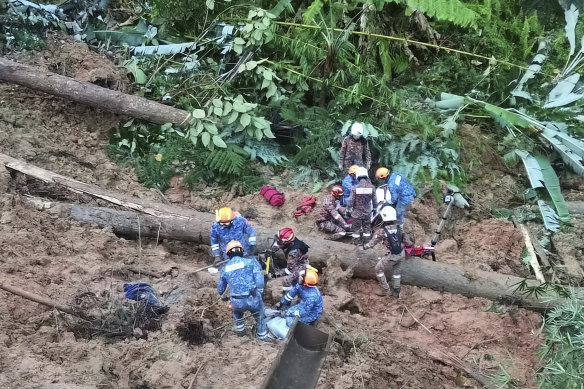 Civil Defence personnel search for missing campers after a landslide hit a campsite in Batang Kali, Malaysia, on Friday.