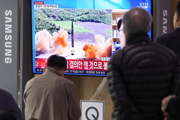 People watch a TV showing a file image of North Korea’s missile launch during a news program.