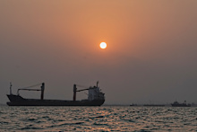 The sun sets over commercial vessels anchored in the Strait of Hormuz off Bandar Abbas, Iran.