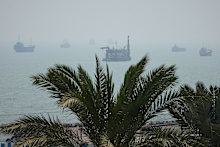 A floating dredging platform and commercial vessels lie anchored amid haze in the Strait of Hormuz off Bandar Abbas, Iran, Monday, Sept. 7, 2026. (AP Photo/Vahid Salemi)