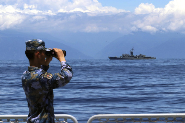 A People’s Liberation Army member looks through binoculars  towards Taiwan’s frigate Lan Yang during military exercises on August 5.