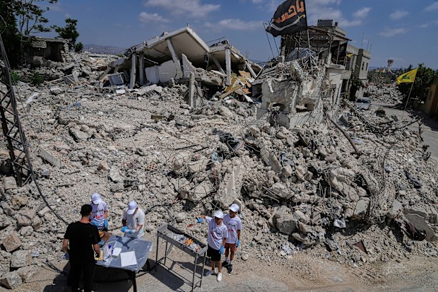 Lebanese activists distribute sandwiches in front of houses that were destroyed in Israeli strikes during the war with Hezbollah in Froun village, southern Lebanon, Thursday, July 16, 2026. (AP Photo/Mohammed Zaatari)