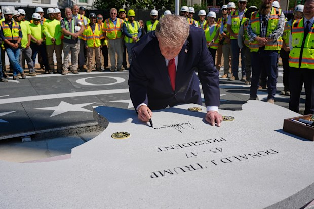 President Donald Trump signs a stone that will be part of the new White House helipad.