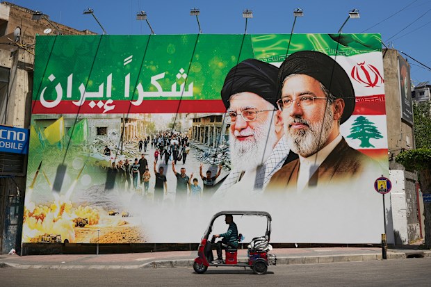 A man rides a scooter past a giant billboard that shows the late Iranian leader Ayatollah Ali Khamenei and Iranian Supreme Leader Ayatollah Mojtaba Khamenei.
