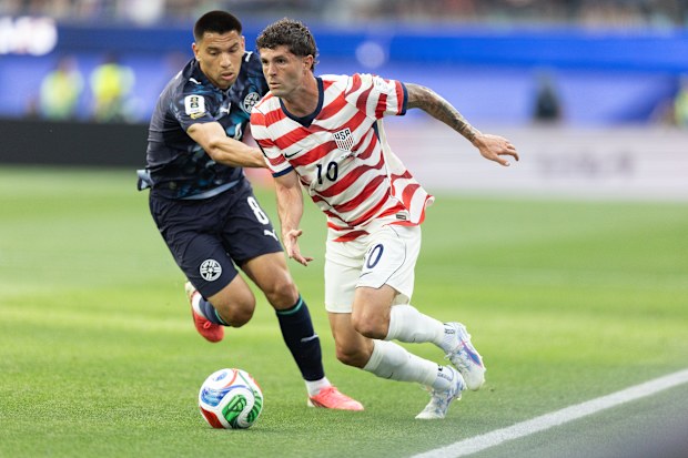Christian Pulisic, the USA's biggest superstar, dribbles past a Paraguayan opponent.