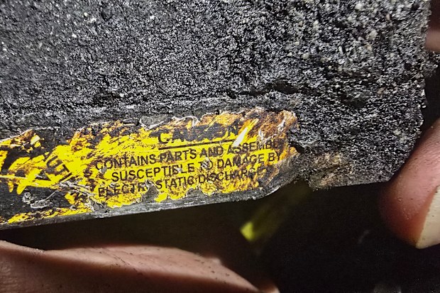 A person holds a fragment of a projectile bearing a warning in English at a site that Iranian media said was hit in a U.S. strike in Kuhestak, southern Iran, early Wednesday, Sept. 2, 2026