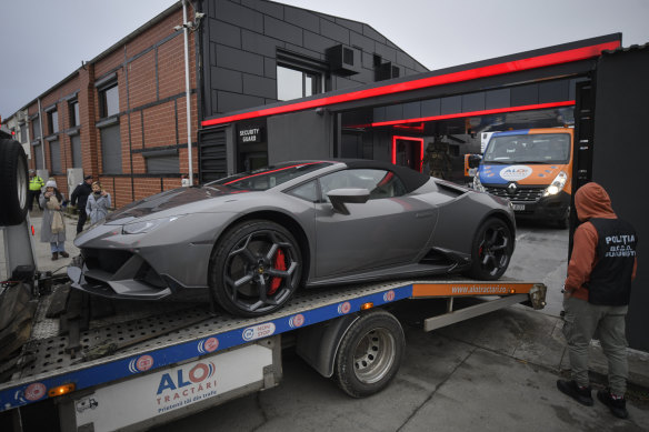 A police officer looks on as a luxury vehicle which was seized in a case against media influencer Andrew Tate, is towed away, on the outskirts of Bucharest.