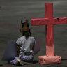 Girls sit next to a cross to remember murdered women in Mexico City, during the national "A day without women" strike on Monday.