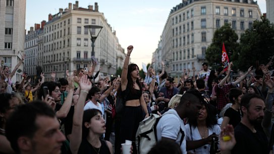 People stand in a square as they react to projected results after the second round of the legislative elections.