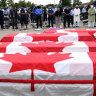 Mourners pray as caskets draped in Canadian flags are lined up at a funeral for the four Muslim family members killed by a white nationalist in June 2021.