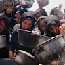 Palestinians struggle to get donated food at a community kitchen in Khan Younis, Gaza Strip.