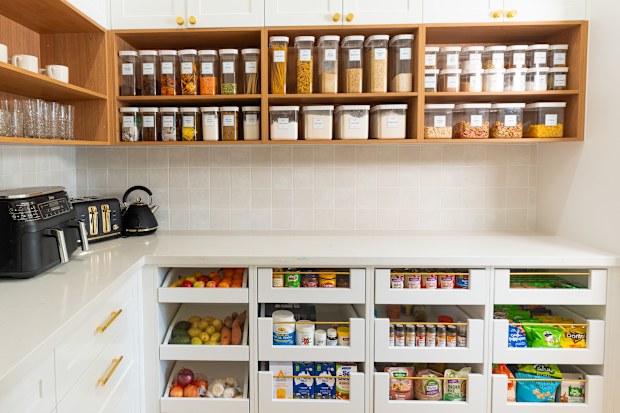 Kitchen pantry organised with decanted baking and cooking supplies on top shelves and snacks below.