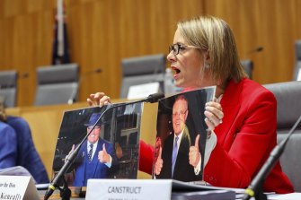 Senator Kristina Keneally holds up photos of Prime Minister Scott Morrison and Canstruct CEO Rory Murphy during a Senate Estimates hearing at Parliament House in Canberra