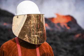 A person wears protective gear while standing close to the lava flowing from Fagradalsfjall volcano in Iceland on Wednesday.