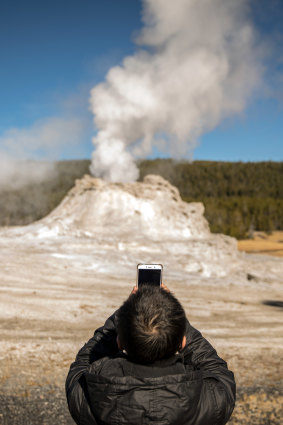 A visitor photographs Castle Geyser in Yellowstone National Park last month.
