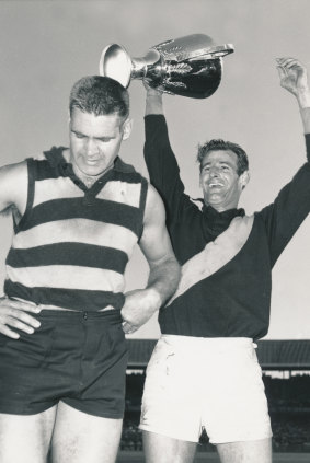 Richmond captain Fred Swift holds aloft the premiership cup, beside Geelong captain Polly Farmer. 