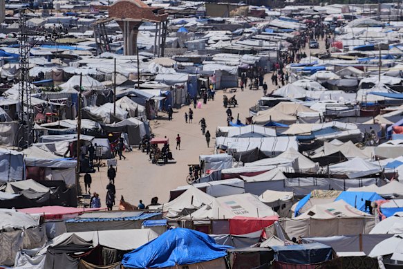 Displaced Palestinians walk through a makeshift tent camp in the Muwasi area of Khan Younis.