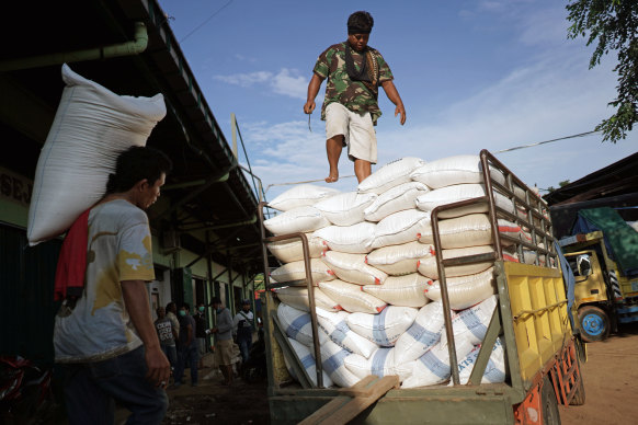 A worker carries a sack of rice while loading a truck at a grain market in Jakarta, Indonesia.