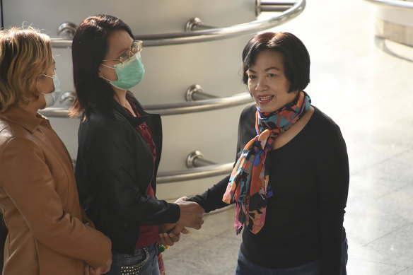 The former civil servant identified only by her first name Anchan, right, greets friends as she arrives at Bangkok Criminal Court to be sentenced.