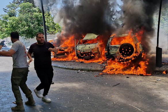 Un uomo corre davanti ad auto in fiamme a seguito di un attacco aereo israeliano nella città portuale meridionale di Sidone, in Libano, il 10 giugno.
