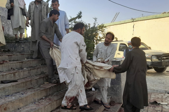 People carry a victim from a mosque following a bombing in Kunduz province, northern Afghanistan.