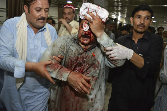 Volunteers rush an injured person to a hospital following a suicide attack on an election rally in Peshawar, Pakistan, earlier this month.