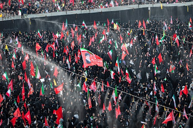 Mourners process under a cooling mist spray in central Tehran.