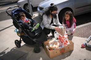 Zeina, with children Jason and Selena, 
picks up a box of groceries. 